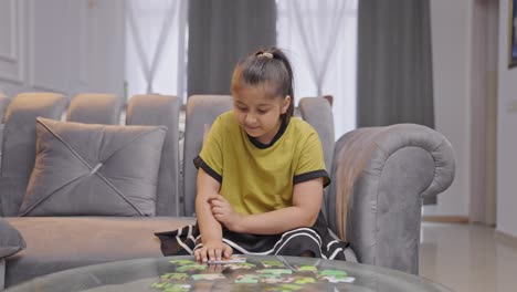 Confused-Indian-kid-girl-trying-to-solve-a-jigsaw-puzzle