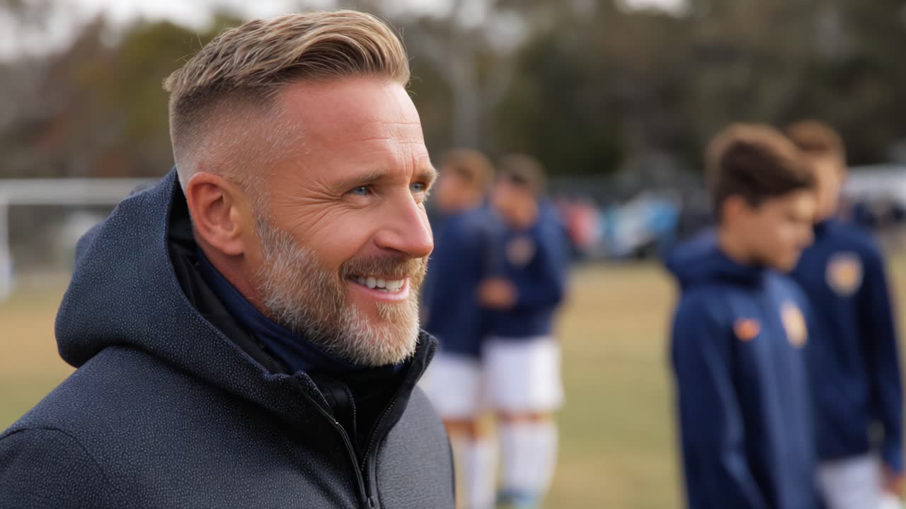 A Joyful Coach Observes His Team During Practice, Exuding Confidence and Enthusiasm as Young Players Prepare for Their Next Challenge