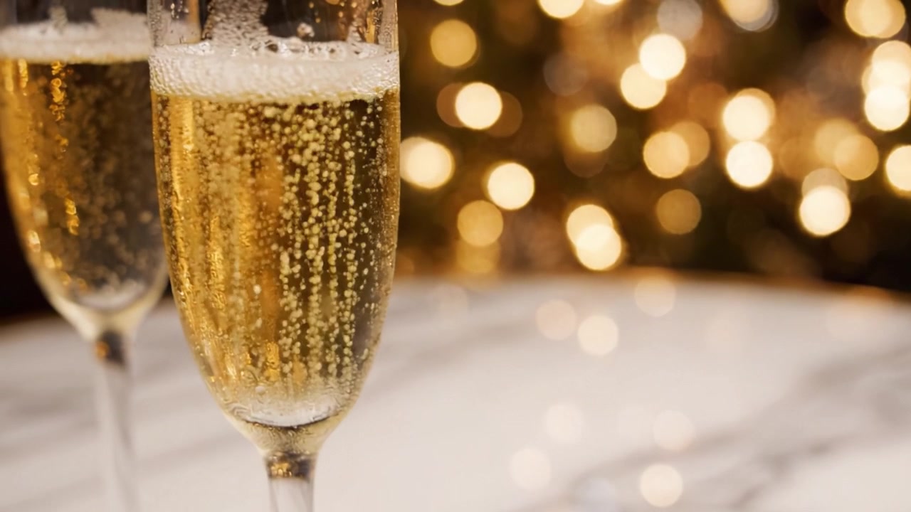 Calici di spumante celebrativi con bollicine su uno sfondo delicatamente illuminato, perfetti per occasioni festive come Capodanno, anniversari o incontri speciali.