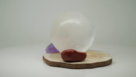 una bola de cristal blanca redonda encima de una artesanía de madera con dos piedras preciosas en ambos lados - primer plano