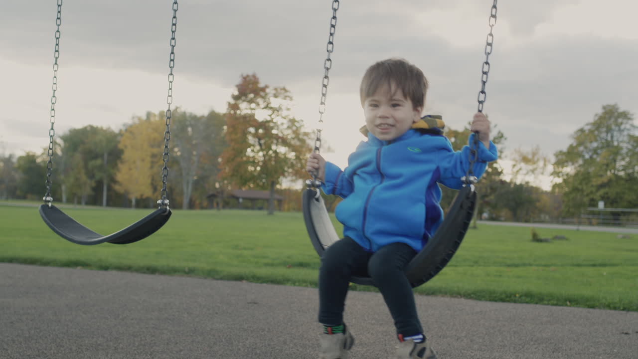 niño asiático monta un columpio en el patio de recreo en el parque