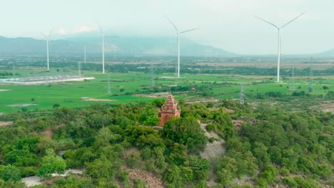 drone view of porome tower , ancient tower of champa in ninh thuan province, far away is a wind turbine farm combine with solar power station, central vietnam