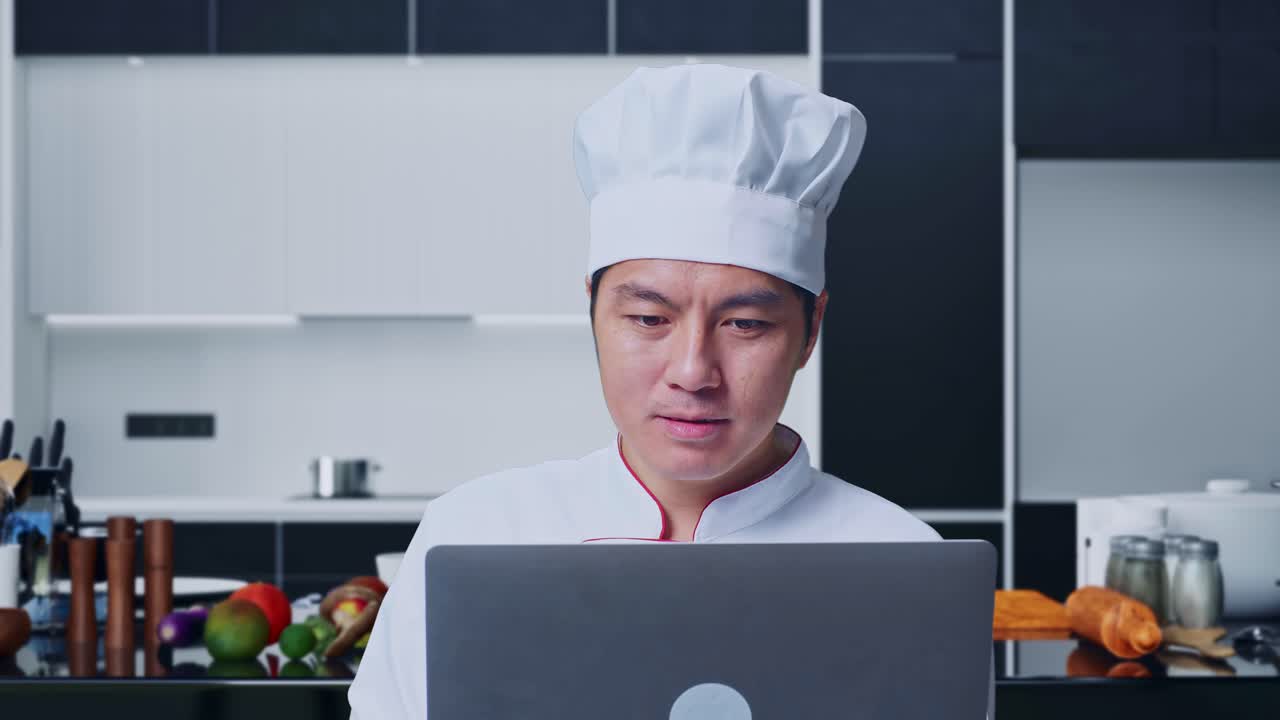 집 주방에 서 있는 동안 노트북을 사용 하고 을 가리키는 아시아인 요리사 의 근접 사진