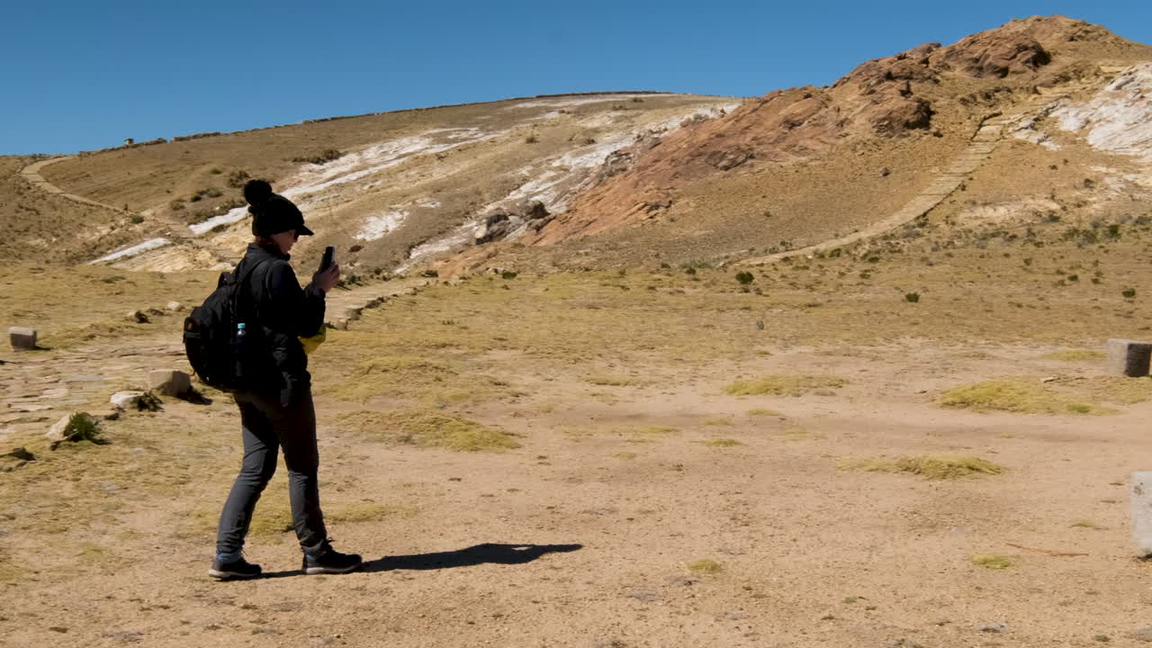 Watch a tourist capturing the historical Ceremony Table on Isla del Sol, Copacabana, Bolivia, with their camera