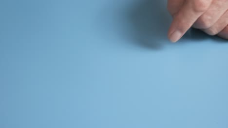 a man plays with an origami frog made from green paper