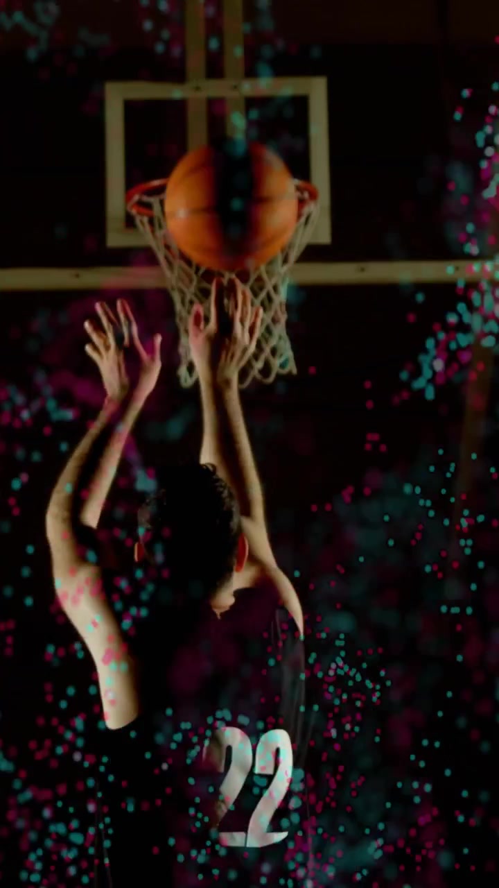 Video verticale: Giocatore di pallacanestro che alza la palla, mirando al canestro mentre un effetto sovrapposto ciano e rosa si alza.