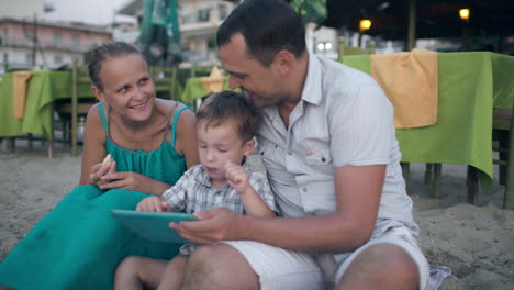 Dreiköpfige-Familie-Im-Resort-Mit-Tablet-PC