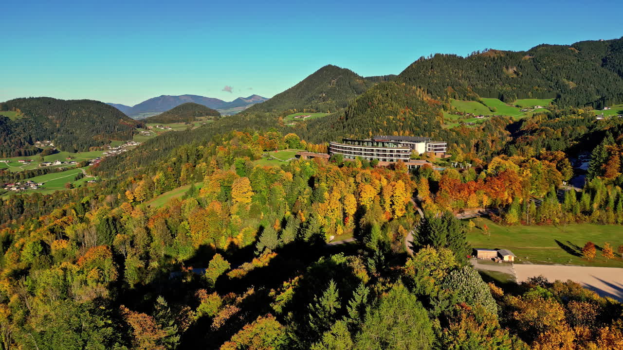 공중 드론은 뒤로 움직이고 있으며, 아침 시간 동안 산의 기?? 에 있는 아름다운 푸른 식물이 내려다보이는 계곡의 리조트 위를 습니다.