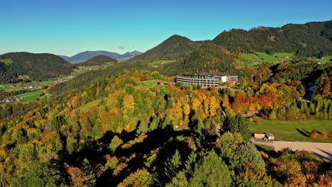 aerial drone backward moving shot over resort in the valley overlooking beautiful lush green vegetation at the foothill of the mountains during morning time