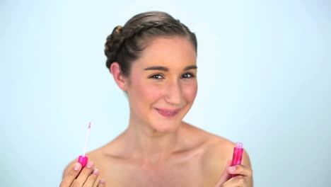 Smiling-young-woman-applying-lipgloss-on-her-lips