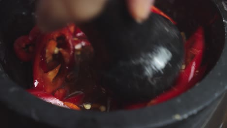 mashing sauce ingredients inside black ceramic bowl