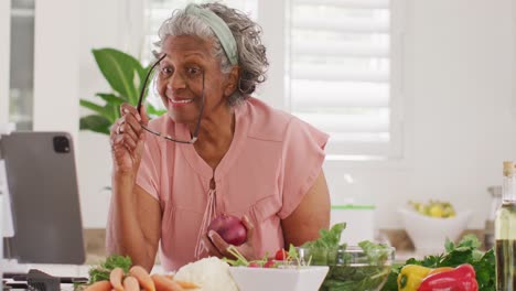 Glückliche-ältere-Afroamerikanische-Frau,-Die-In-Der-Küche-Kocht-Und-Ein-Tablet-Benutzt