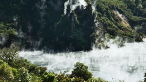 Toma-Panorámica-De-Vapor-De-Azufre-Tóxico-Flotando-Sobre-El-Lago-Místico-Caliente-Durante-La-Luz-Del-Sol---Waimangu,-Nueva-Zelanda