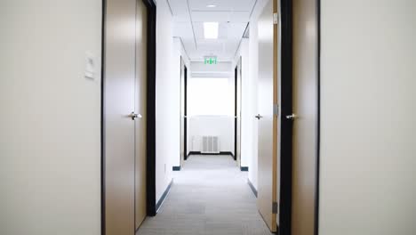 an illuminated office corridor showcasing minimalist design with open doors and soft lighting for a welcoming professional environment