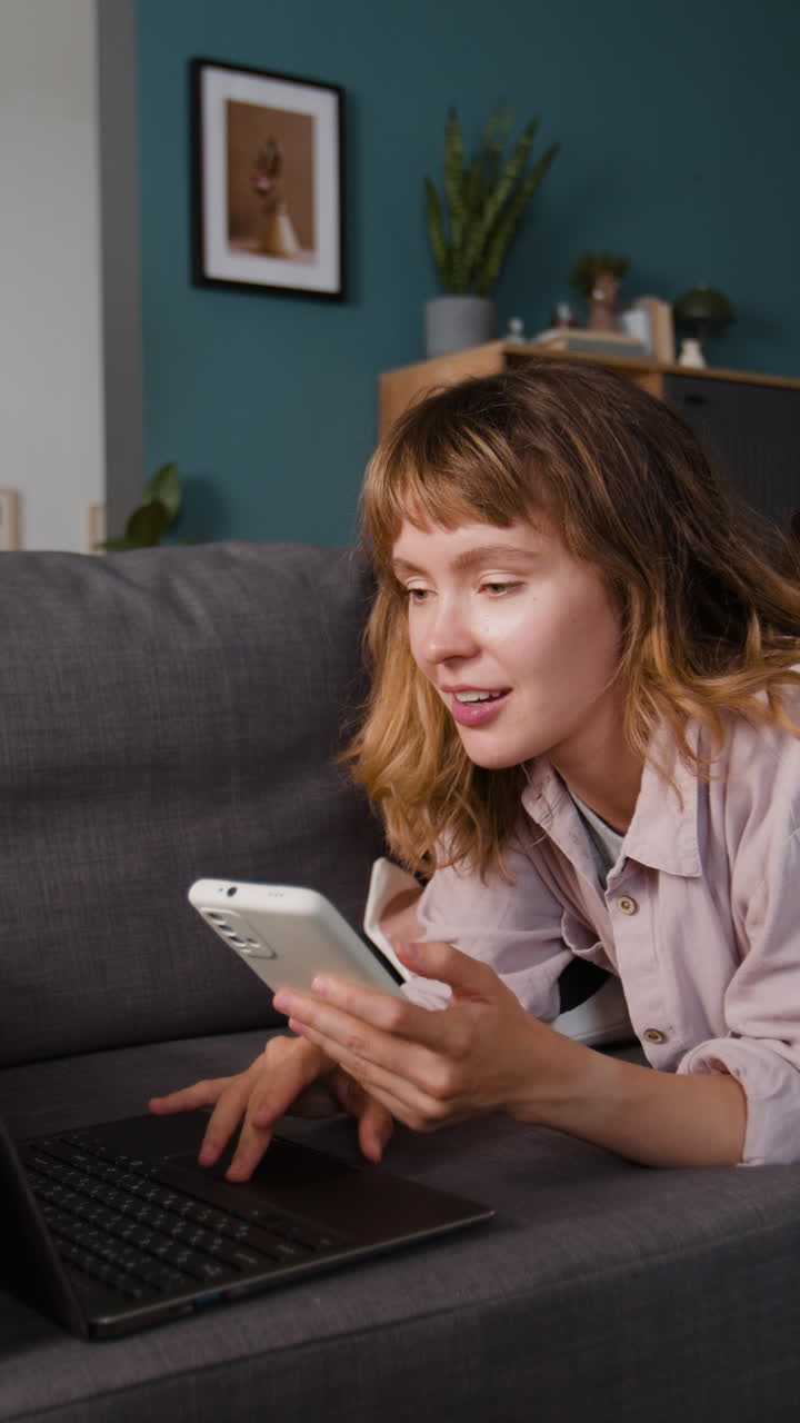 Woman using phone and laptop on couch