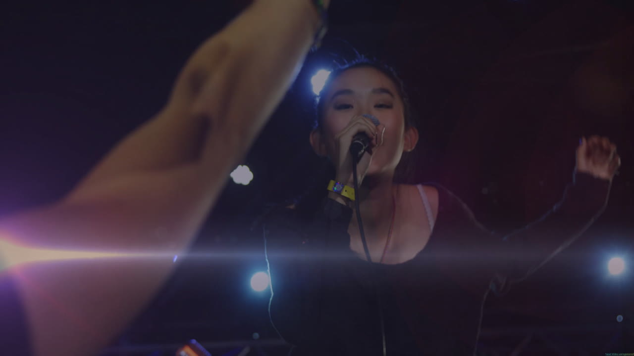 Female singer performing on concert stage, with animated music notes and lens flare graphics