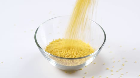 millet falling in a glass bowl on white background. healthy organic food diet concept. fresh natural food ingredient