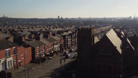 Aerial-view-reveals-rows-of-historic-terraced-houses-with-a-long-road-leading-towards-the-bustling-town-centre,-zoom-out-shot