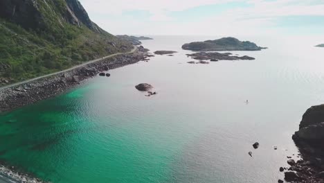 Drone-shot-of-a-road-over-the-sea-with-rocky-cliffs-on-the-side