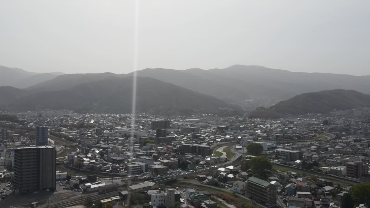 Aerial View Over Matsumoto City In Nagano Prefecture On Bright Sunny Day With Single Lens Flare. Dolly Back Shot