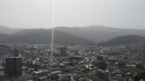 aerial view over matsumoto city in nagano prefecture on bright sunny day with single lens flare. dolly back shot