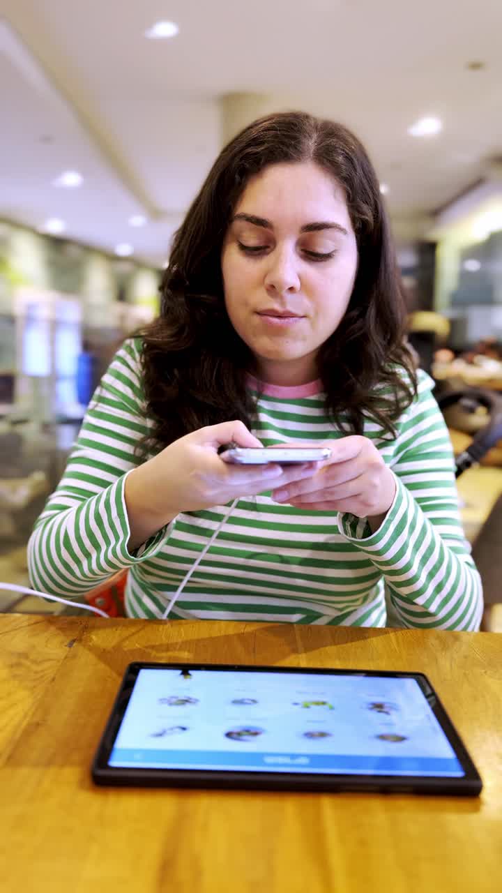 Young woman in cafeteria taking a picture with her mobile phone of the menu.