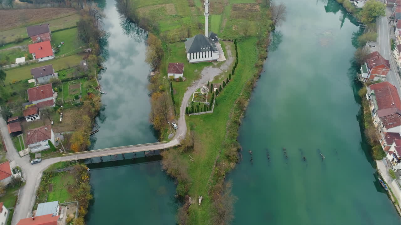 Aerial view of a river that splits in two ways. Bridge connecting to small island with church. Jablanica, Bosnia and Herzegovina