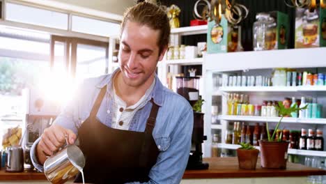 smiling waiter making cup of coffee at counter