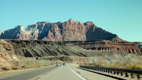 Driver-perspective-of-red-stone-mountain-ridge-above-desert-highway