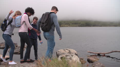 four friends walking by the edge of a lake