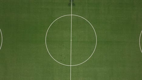 drone shot of a football field with birds eye view - drone is ascending from the kick off, revealing the whole pitch