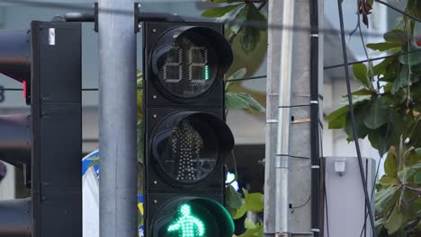 close-up view of pedestrian traffic light changing from green to red with countdown timer.