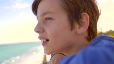 boy looking out over oceanside railing