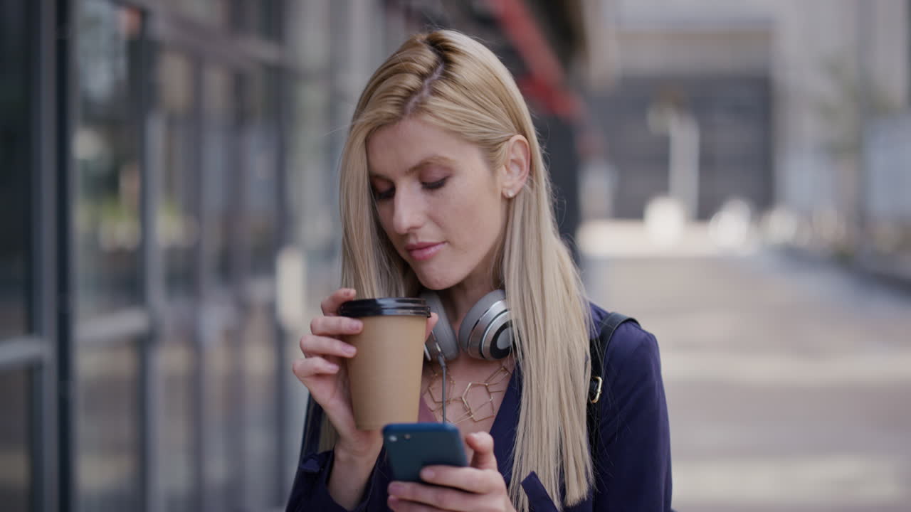 ritratto giovane bellissima donna bionda che usa lo smartphone in città beve caffè si gode uno stile di vita urbano rilassato navigando messaggi online scrivendo messaggi sul telefono cellulare in slow motion