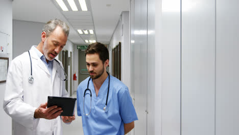 Male-doctor-and-colleague-discussing-over-digital-tablet