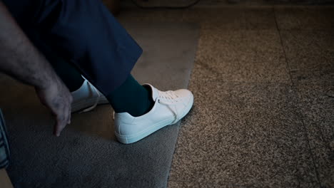 man tying laces on white sneakers