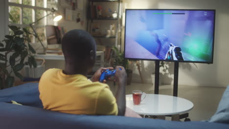 black man playing shooter video game at home