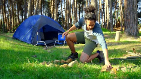 Man-preparing-bonfire-in-the-forest-on-a-sunny-day-4k