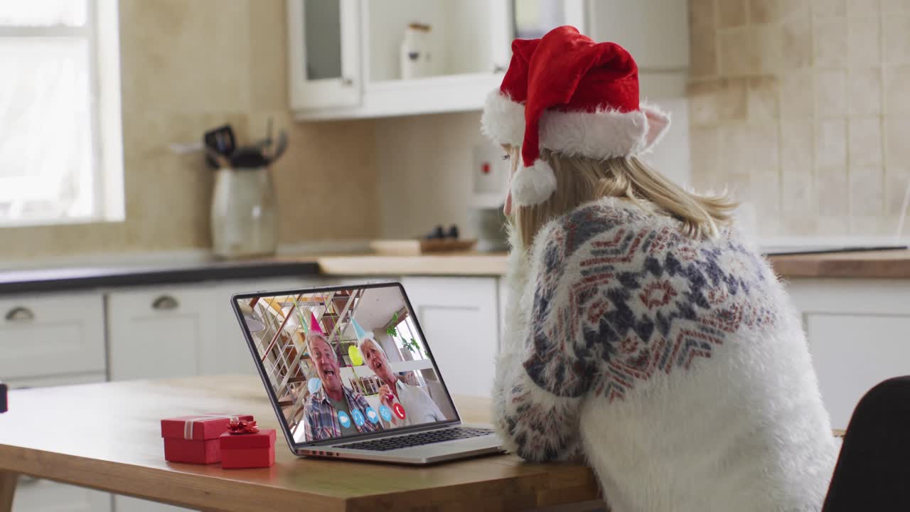 mujer caucásica con sombrero de santa usando computadora portátil en video chat durante la navidad en casa