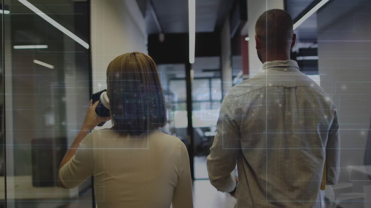 Un hombre sujetando una carpeta y una mujer bebiendo café caminando por el pasillo de una oficina activando superposiciones de escaneo de datos