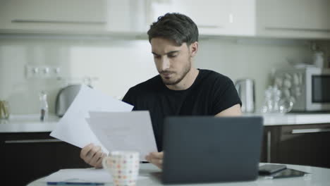 Worried-business-man-looking-papers-at-home-workspace.-Portrait-of-upset-man