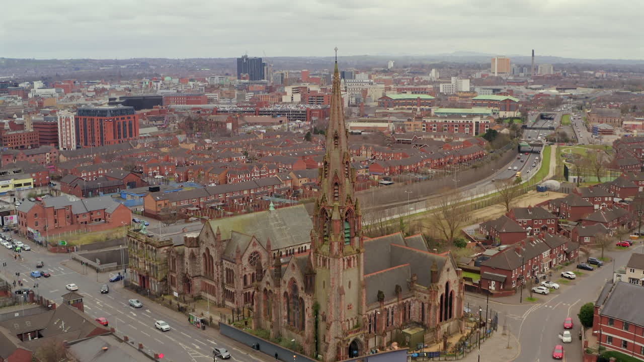 Close aerial pullback of Carlisle Memorial Church spire with Belfast skyline and cloudy skies, establishing overview