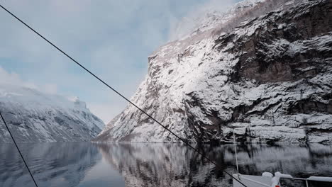 Vídeo-En-Primera-Persona-De-Un-Viaje-En-Ferry-A-Través-Del-Fiordo-De-Geiranger-En-Invierno,-Que-Presenta-Impresionantes-Vistas-De-Montañas-Cubiertas-De-Nieve,-Un-Cielo-Brillante-Y-Reflejos-En-El-Fiordo.