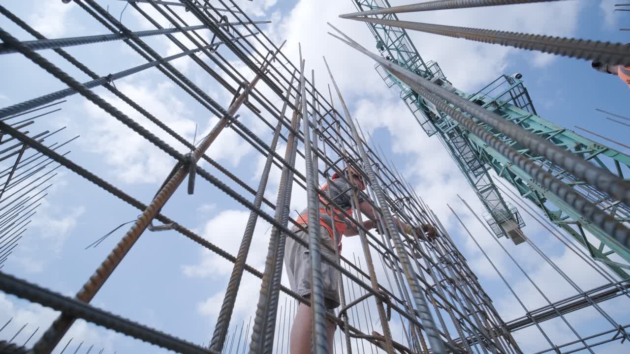 un trabajador utiliza alambre de ataduras de acero para sujetar barras de acero a barras de refuerzo. estructuras de hormigón armado - tejer una jaula de reforzo de metal.