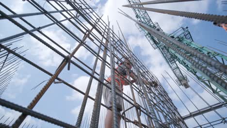 a worker uses steel tying wire to fasten steel rods to reinforcement bars. reinforced concrete structures - knitting of a metal reinforcing cage.