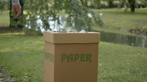 persona tirando papel en la segregación de papelera de basura con fines de reciclaje