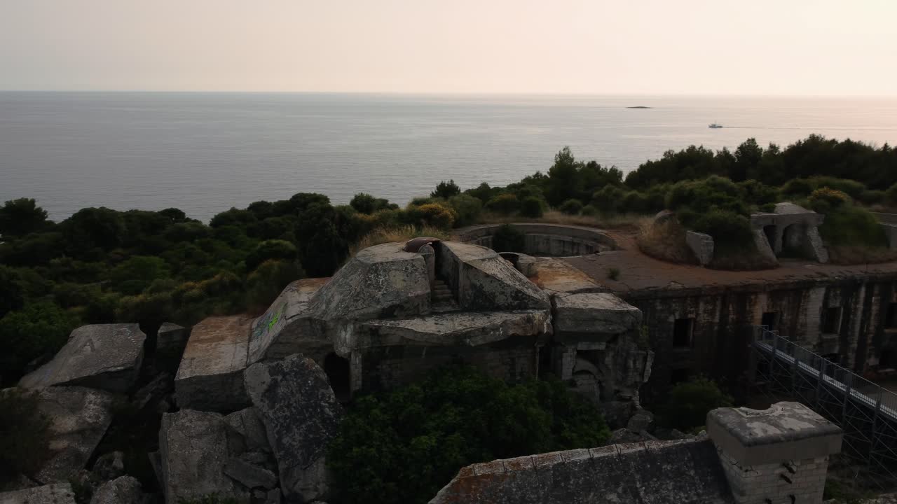 Veduta aerea cinematografica con drone che sorvola una fortificazione storica della Prima Guerra Mondiale, una fortezza costiera sull'idilliaco Mar Adriatico mediterraneo con acqua blu e spiagge nascoste per i viaggi