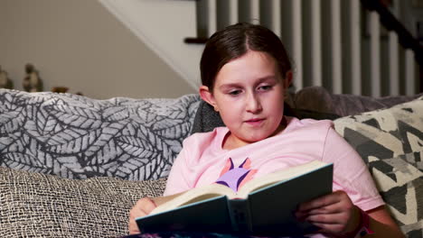 Young girl reading book in living room