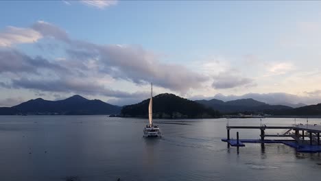 Catamaran-Boat-Cruising-Off-The-Pier-Of-Hanwha-Resort-In-Geojedo-Island,-South-Korea