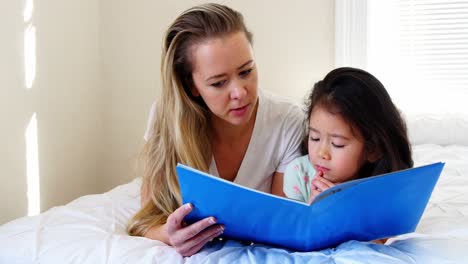 Mother-and-daughter-reading-book-on-bed